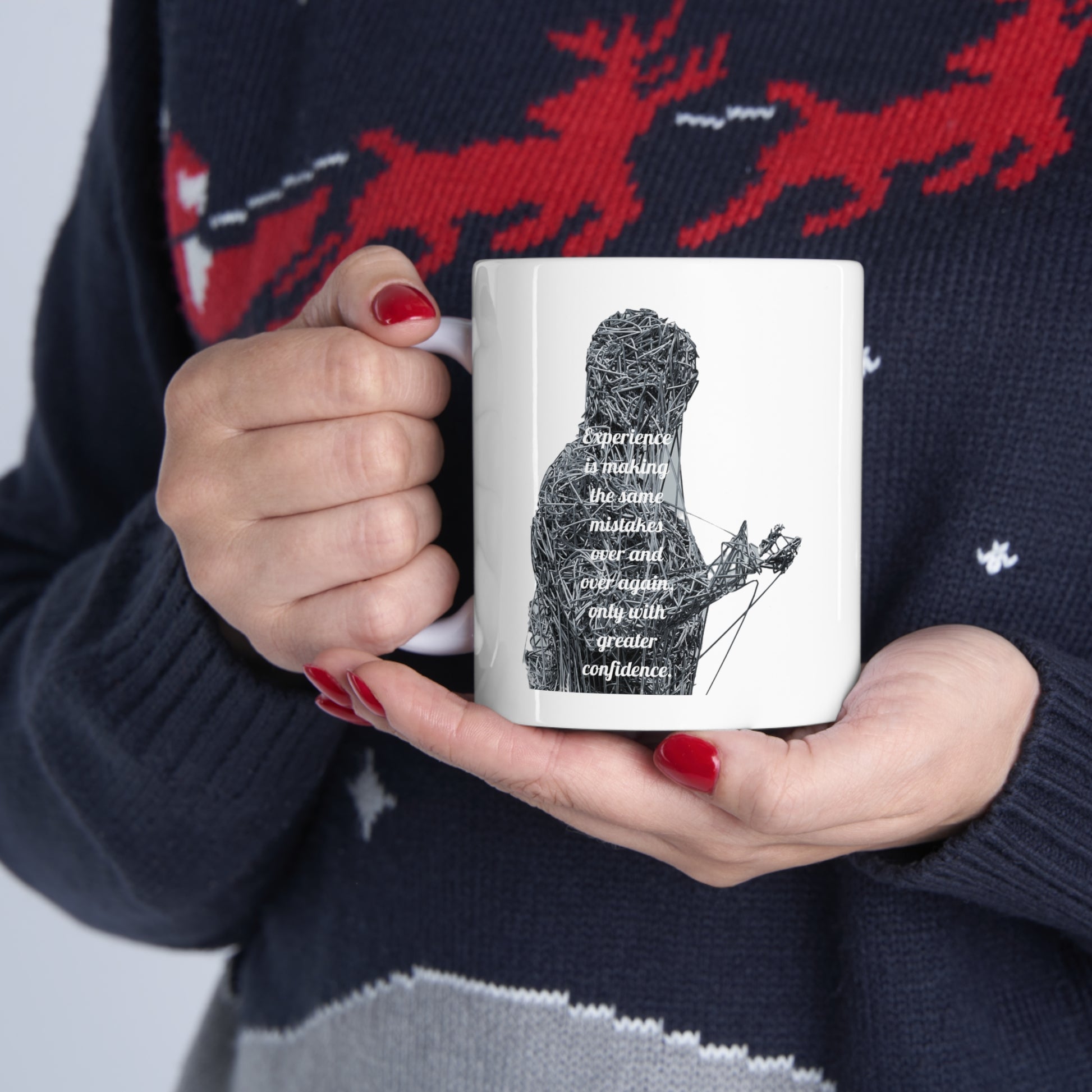 Person in reindeer sweater holding mug with graphic monster "Experience is making the same mistakes"