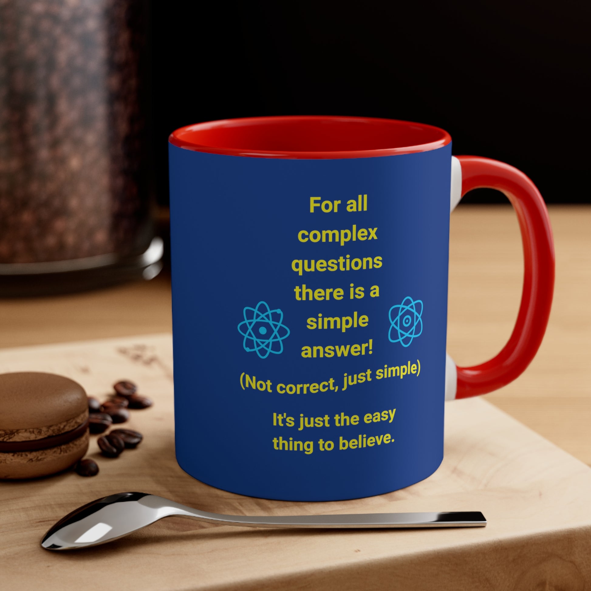 Blue mug with red inside and handle with quote "Complex Questions" on a woodblock by a spoon and cookie.