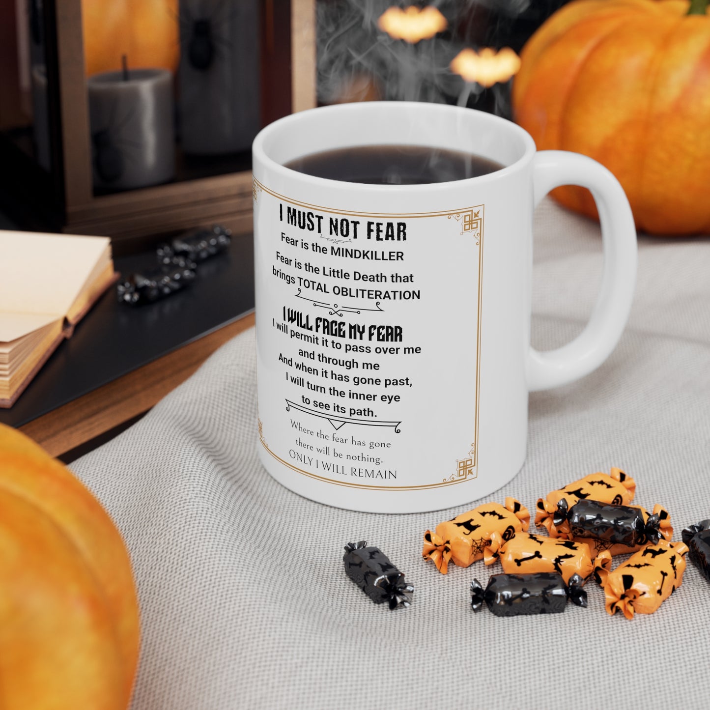 White mug with Dune's "Fear Litany" on a white table cloth by Halloween items.