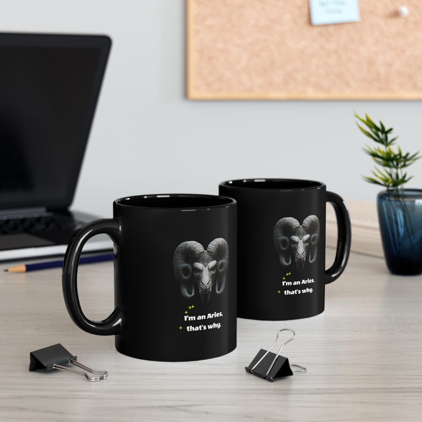 Two Black mug with graphic of Ram figure "I'm an Aries, that's why," sitting on a white work table.