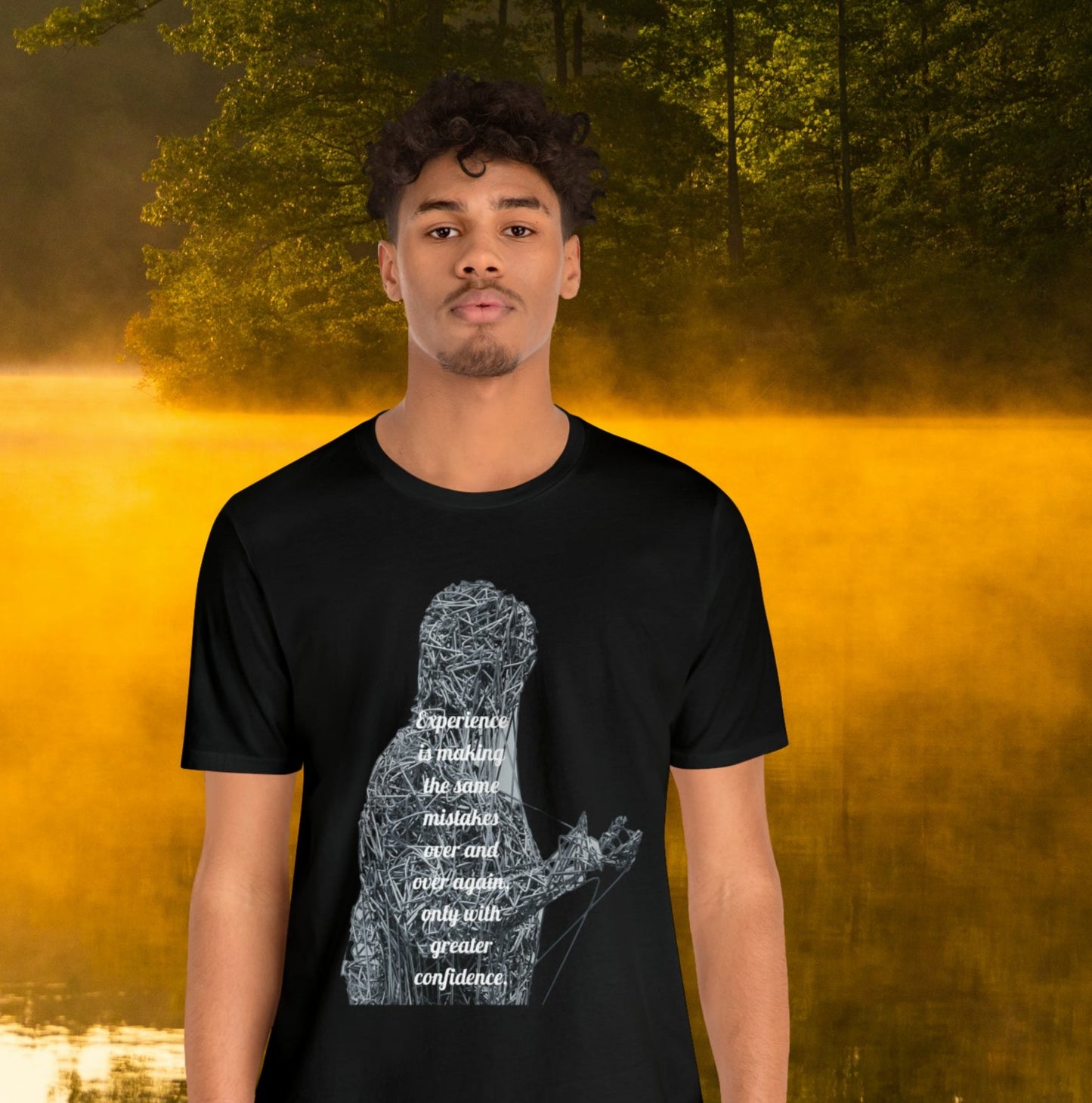 Young man wearing black  tee on golden pond background with "Experience is making the same mistakes" monster graphic.