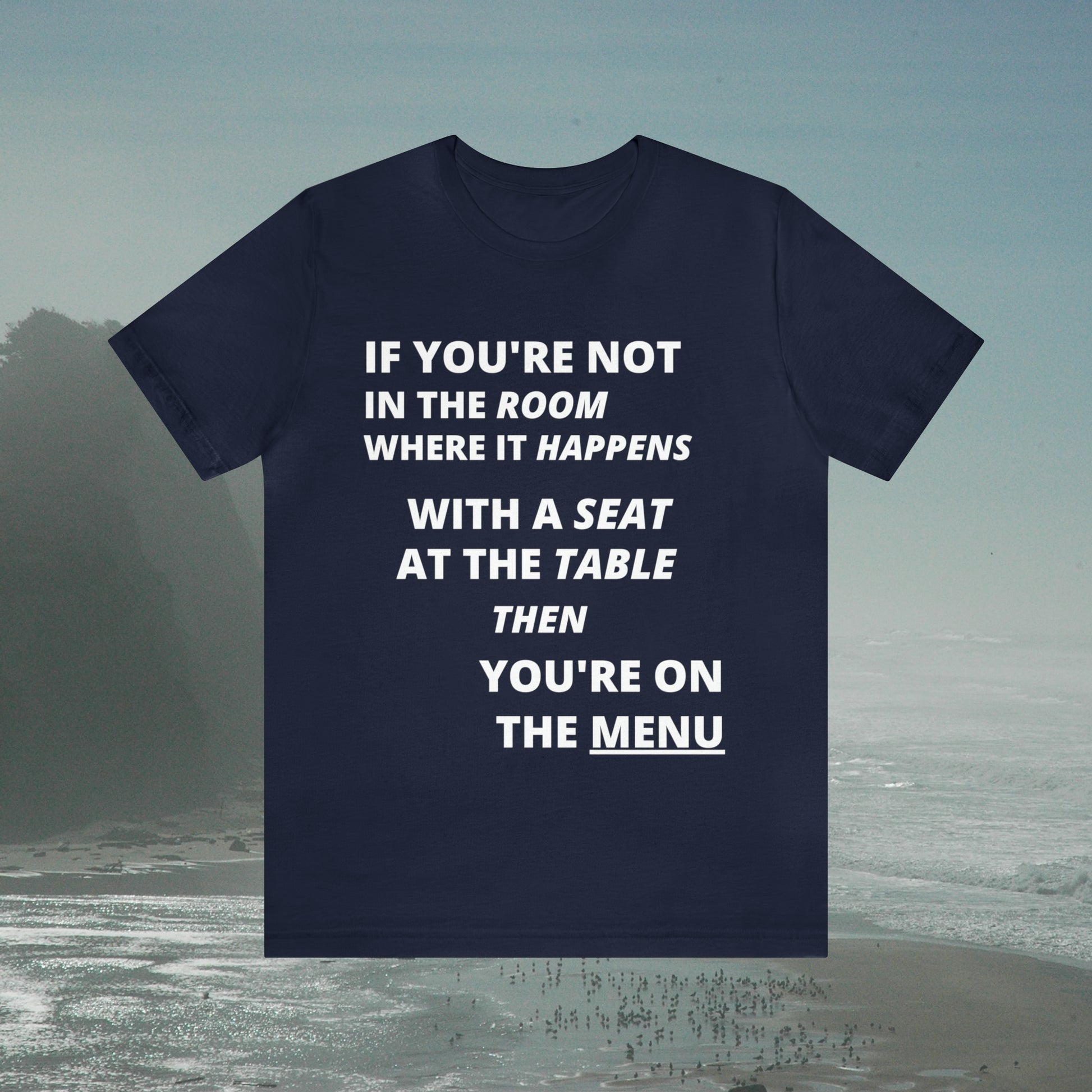 Blue tee with graphic "If you're not in the room...", foggy seashore background.