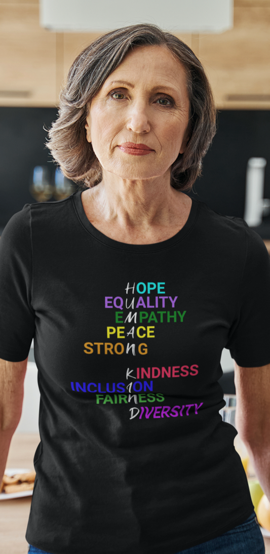 Senior woman leaning on a table wearing a black tee with graphic "Human Kind"