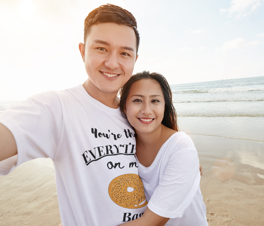 Couple wearing "Everything Bagel" tee on beach taking a selfie