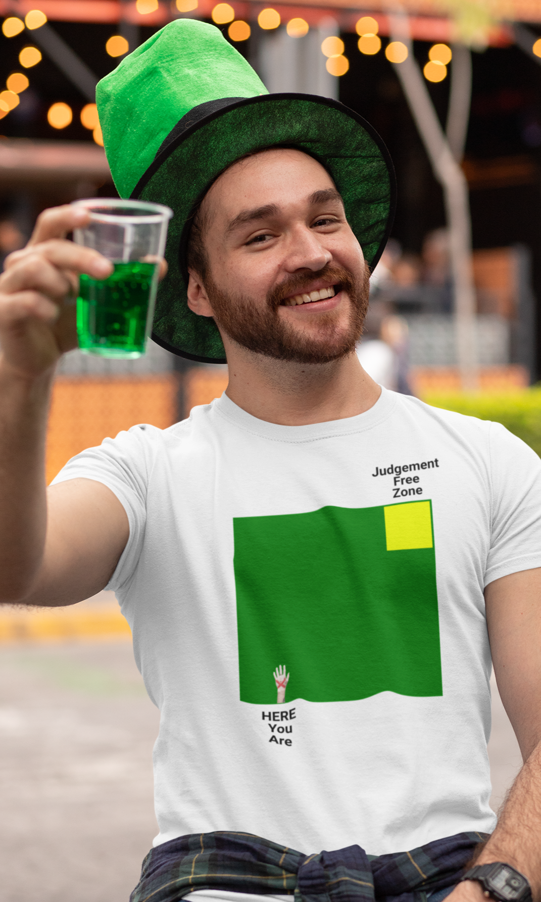 Man at St. Patrick's Day celebration with green hat and beer. wearing graphic tee of "Judgement Free Zone"