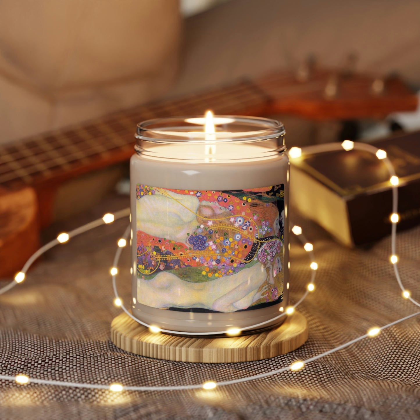 Scented Soy Candle of "Cinnamon Vanilla" with Klimt"Water Spirits' art, lit, with LED chain, with uke and book in background