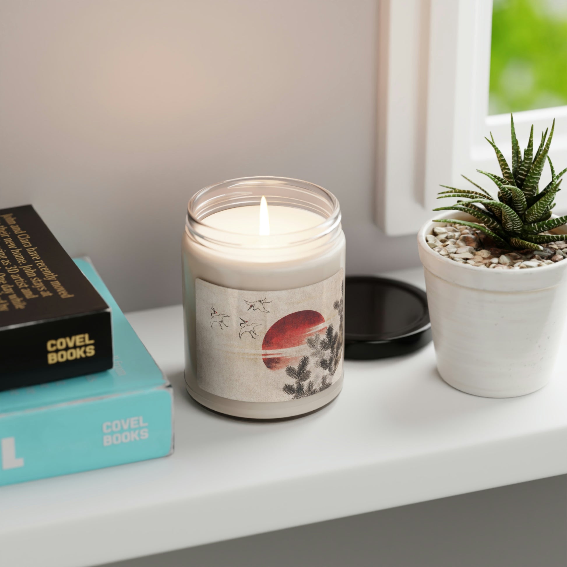 "Clean Cotton" Scented Soy Candle  jar with Hokusai print 'birds and sunset' on white table by aloe plant and book