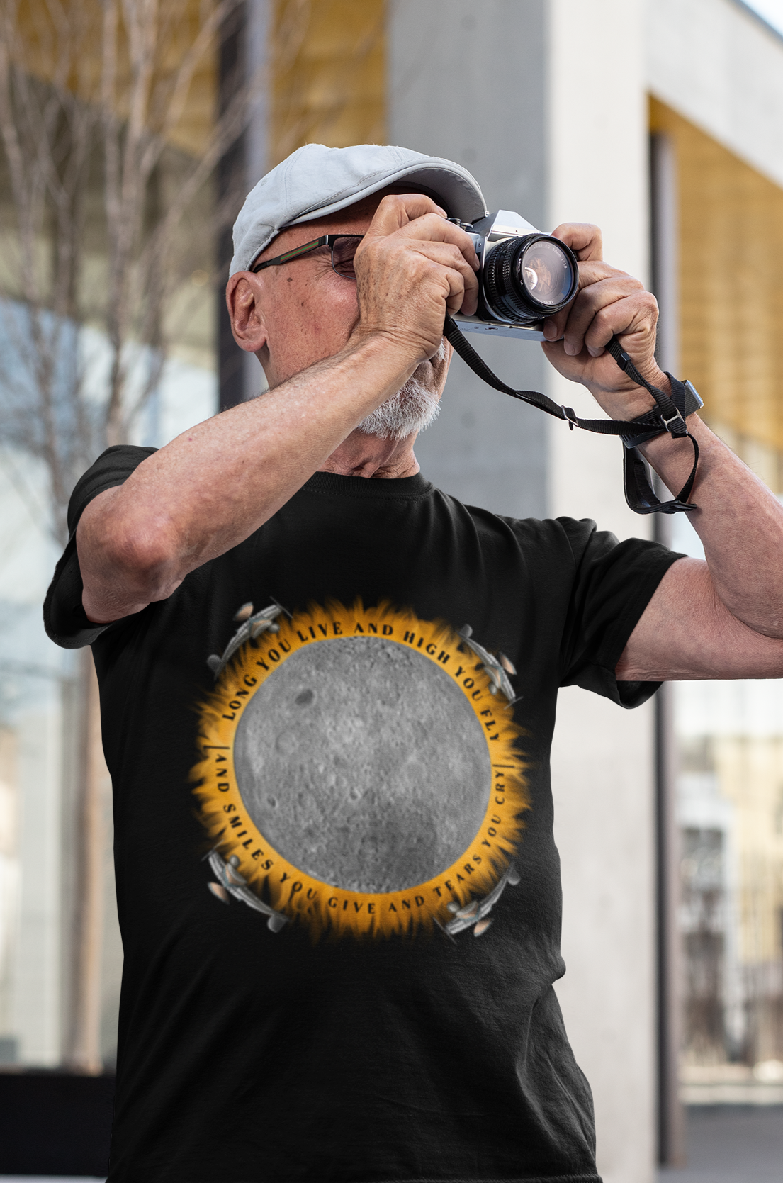 Man in hat taking photo while wearing graphic tee of "Eclipse, from the Dark Side of the Moon"