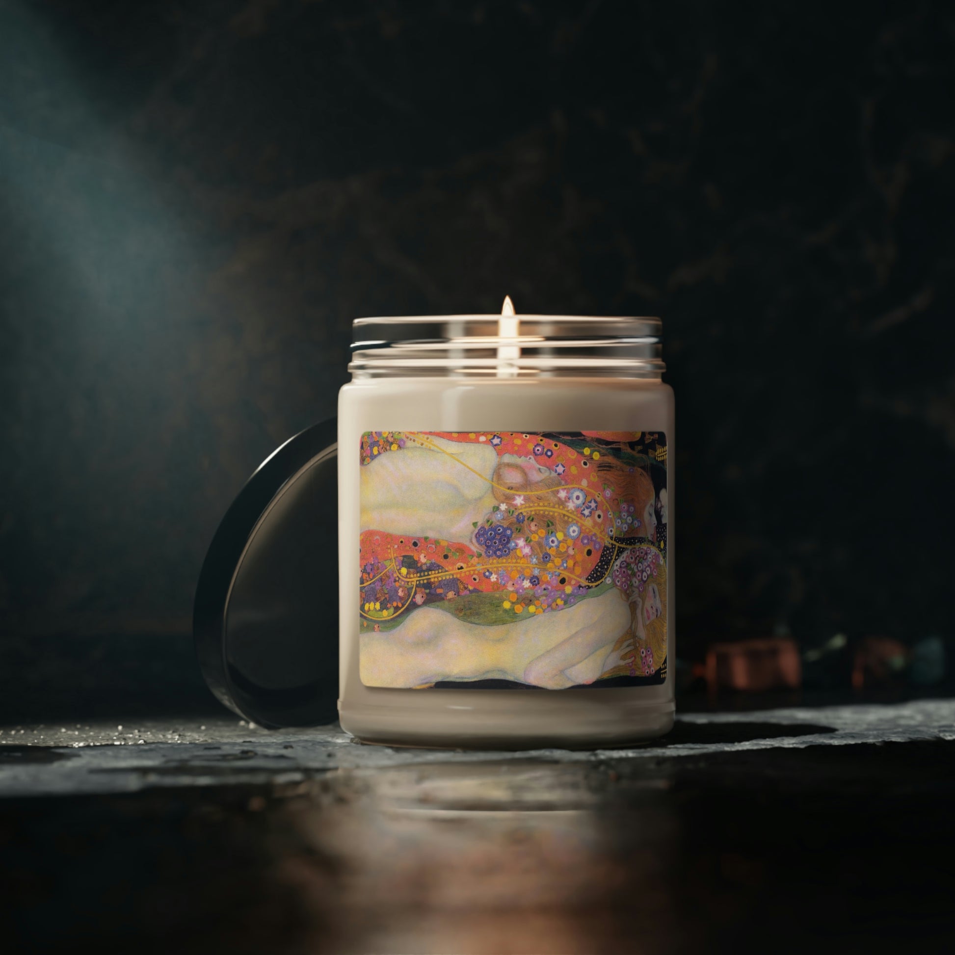 Scented Soy Candle of "Cinnamon Vanilla" with Klimt"Water Spirits' art, lit, on black table with dark background